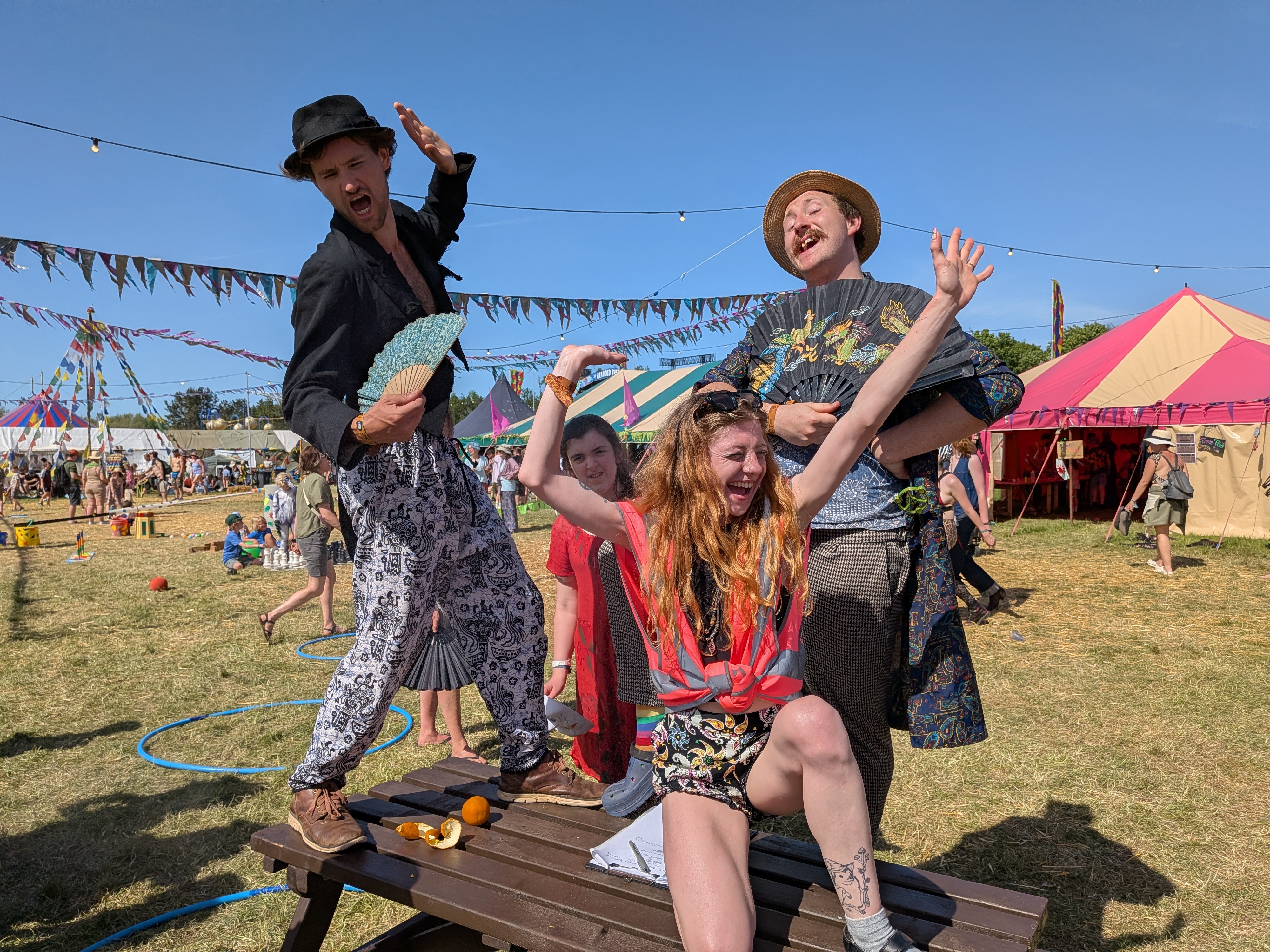 Festival performers posing theatrically in a sunny field during on-site Tarot Interviews event coverage.