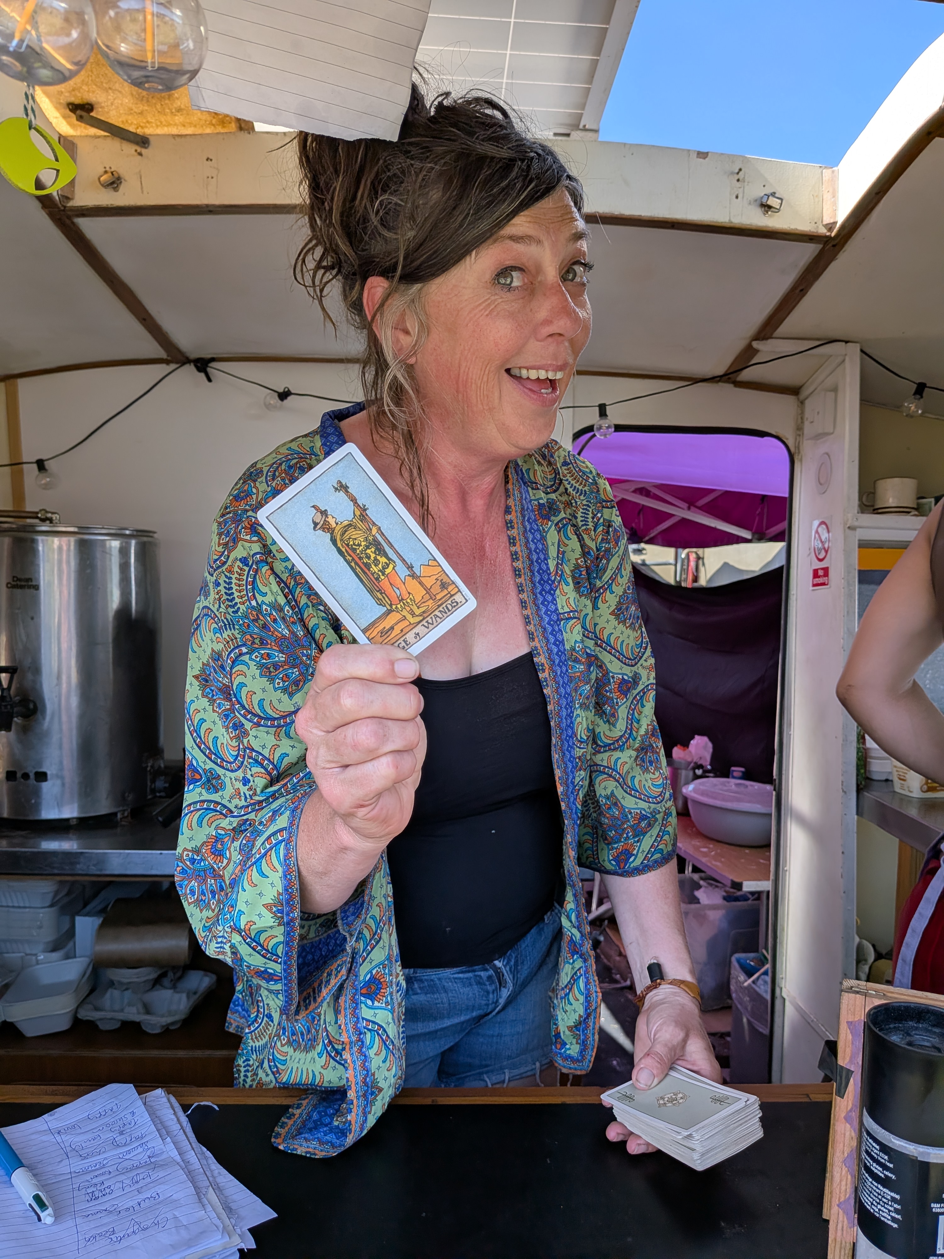Festival food trader holding the Ace of Wands tarot card during a Tarot Interviews recording at a UK festival.